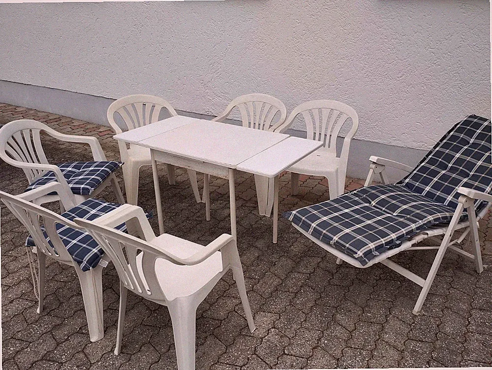 Weiße Kunststoff Gartenmöbel mit ausziehbaren Holztisch und blauen Polstern